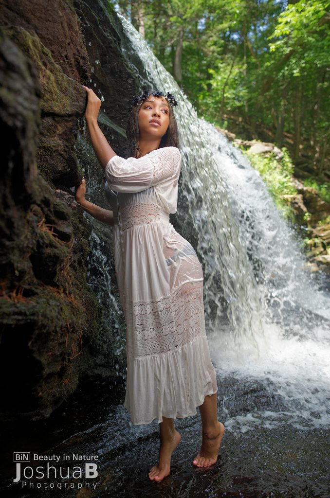beautiful black woman in white dress at waterfall