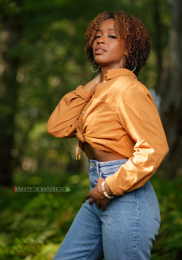 Daisal in nature wearing jeans and tied shirt, ferns and trees background