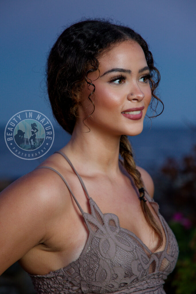 Beautiful high school senior girl wearing halter top posing against a wall near ocean