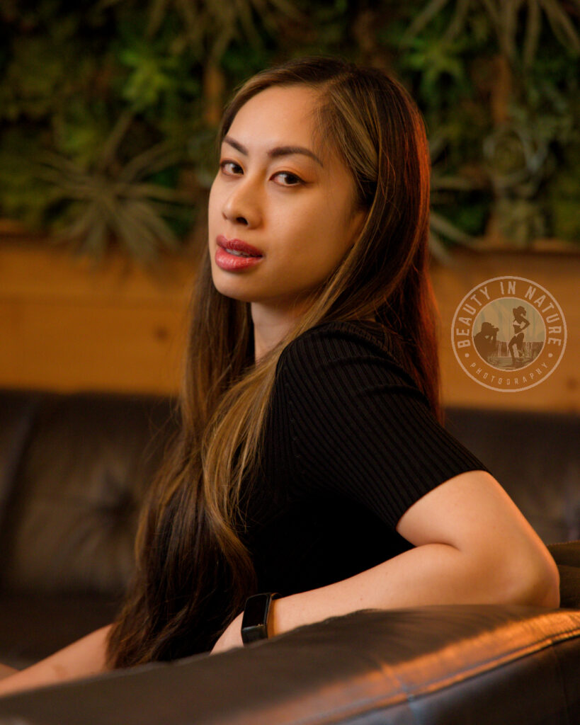Beautiful Korean American woman model esthetician sitting on leather couch with nature background